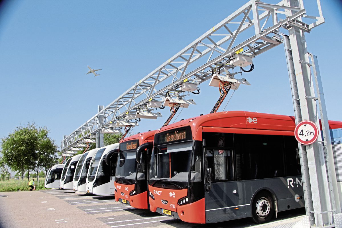 A plane flies over the buses fast charging at Cateringweg depot. Buses from both fleets use these chargers